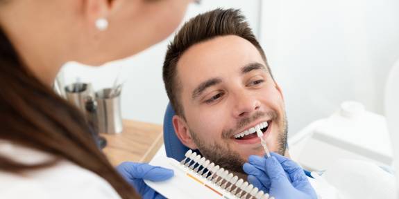 ZFA mit Patient hält eine Palette an Zahnfarben