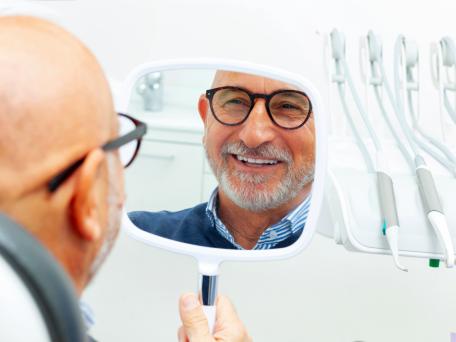 Mann mit Handspiegel im zahnarztstuhl
